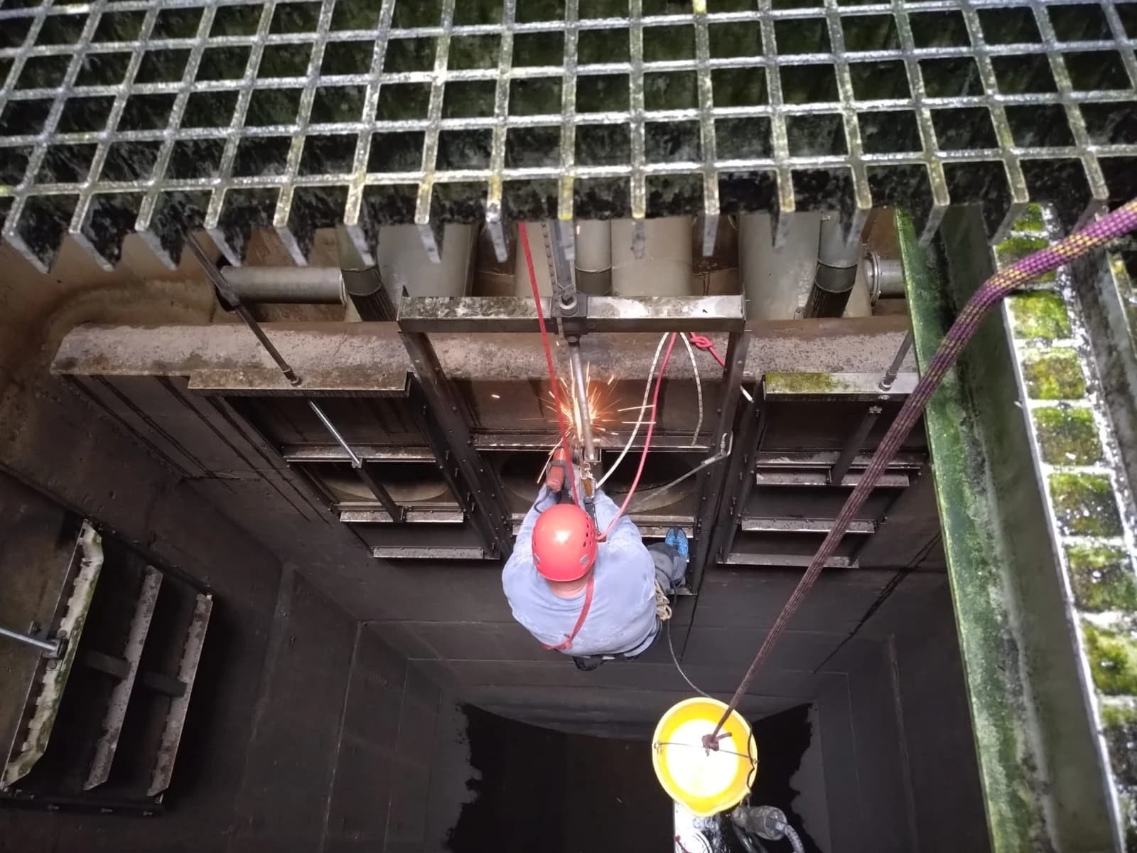 Technik zavěšený na laně svařuje ocelovou konstrukci pod mostem